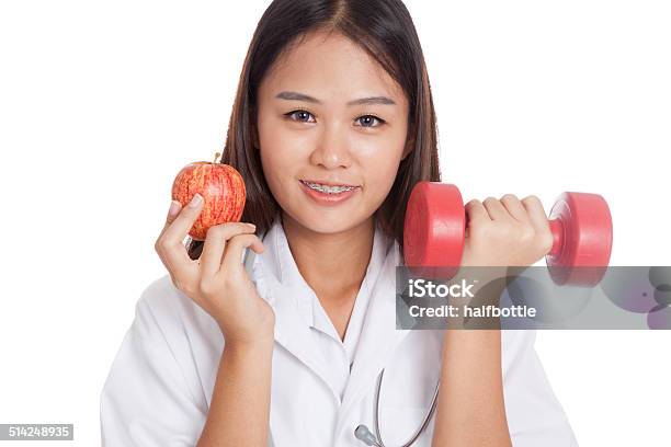 Young Asian Female Doctor Hold Apple And Dumbbell Stock Photo - Download Image Now - Adult, Adults Only, Apple - Fruit