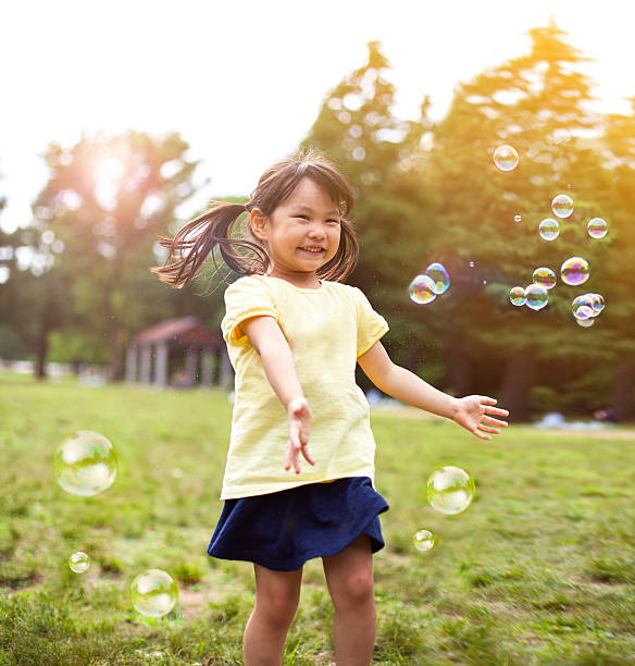 little girl soplando burbujas de jabón - bubble wand bubble child playful fotografías e imágenes de stock