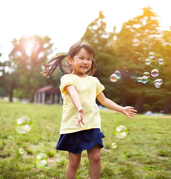 menina soprando bolhas de sabão - bubble wand bubble child playful - fotografias e filmes do acervo