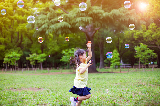 Little girl blowing soap bubbles in park in Tokyo, Japan. Image is taken during Tokyo Istockalypse 2015
