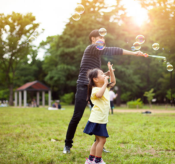 istock Father and daughter having fun in park with Soap Bubbles 514259244