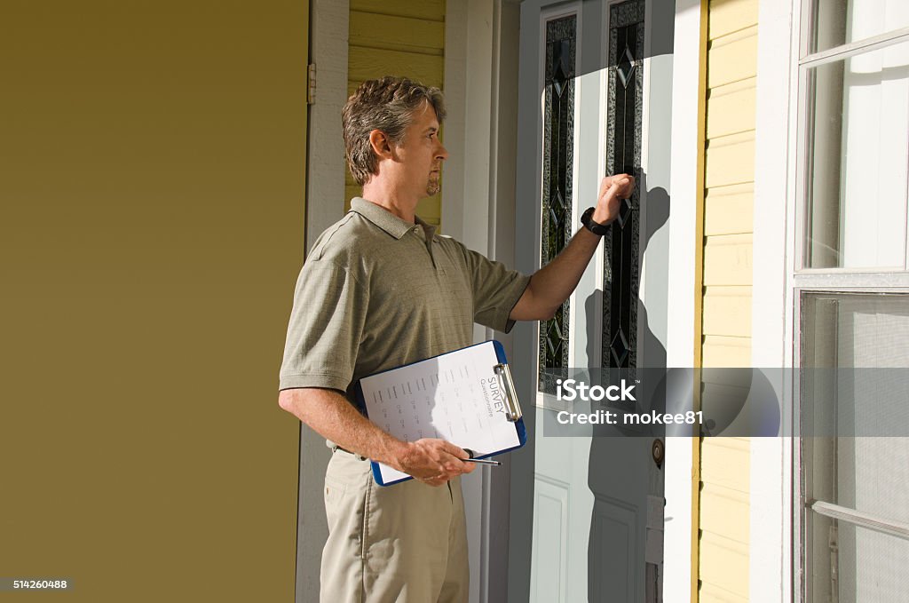 Man doing survey or petition work door-to-door Man knocking on the front door of house doing survey, political campaign or petition signing work door-to-door. Census Stock Photo