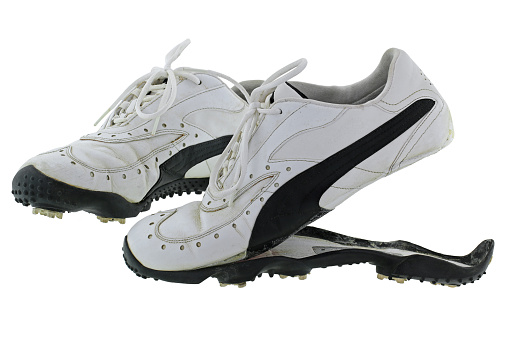 A pair of old and dirty Golf shoes in black and white with split rubber sole, isolated on white