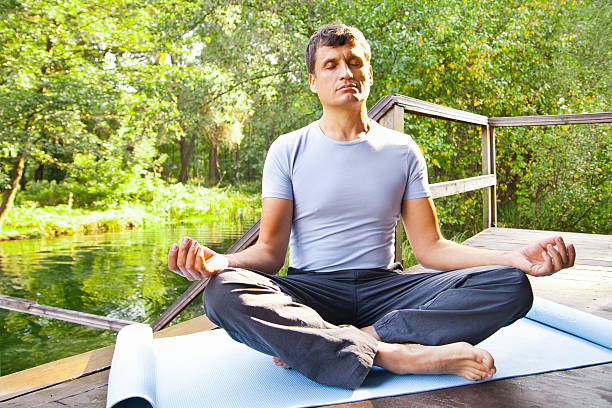 istock young man doing yoga lotus pose in park 514268349