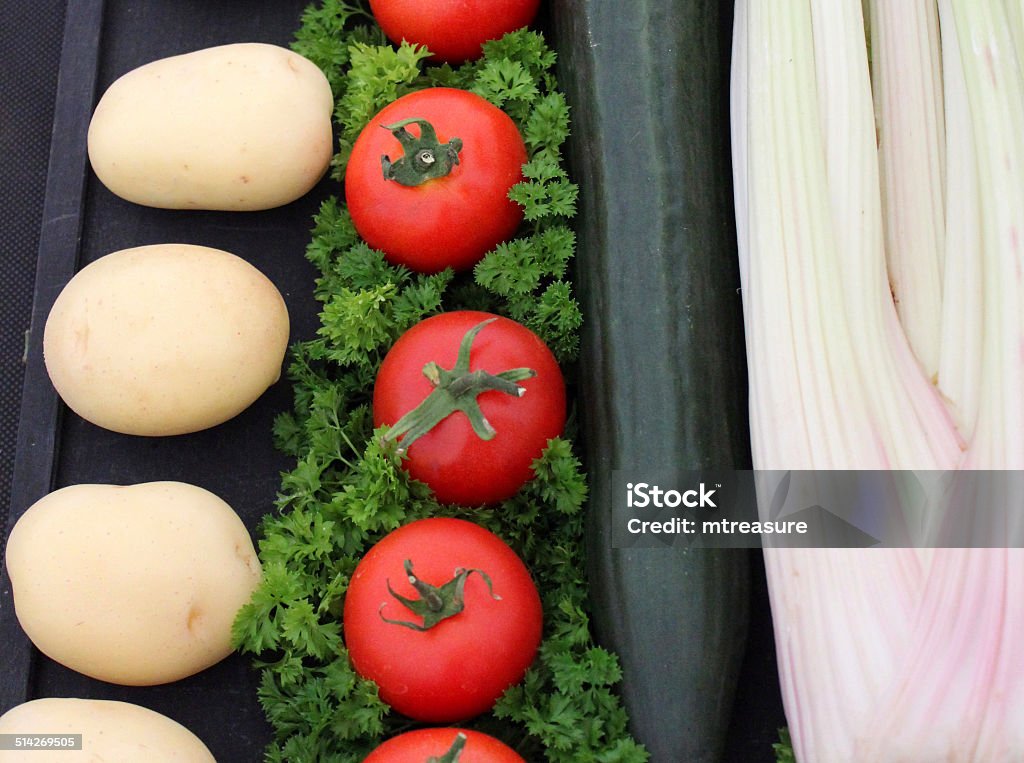 Image of prize-winning vegetables, tomatoes, cucumber, celery, potatoes, flower-show exhibition Photo showing a display of prize-winning vegetables, comprising tomatoes (dressed with parsley garnish), cucumber, celery and a row of homegrown potatoes, displayed in the fruit and veg tent of a flower show exhibition / agricultural show. Agricultural Fair Stock Photo