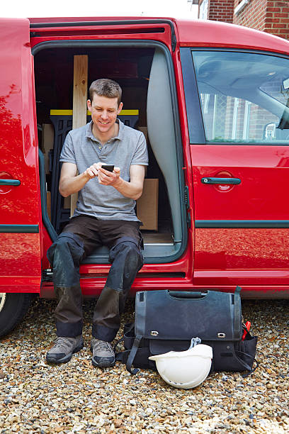 istock Tradesman typing on cell phone while sitting in van 514270411