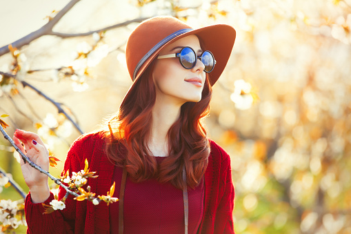portrait of beautiful young woman with black sunglasses standing near blooming tree