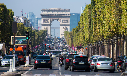 Paris, France - September 13, 2014: Traffic at Avenue des Champs-Élysées with Arc de Triomphe and skyscrapers