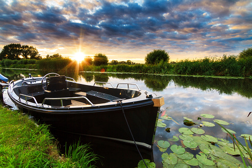 Modern and luxurious synthetic motor sloop in a river in the Netherlands at sunset
