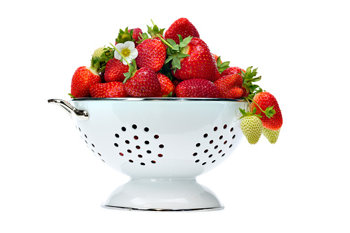 old colander full of fresh strawberries isolated on white