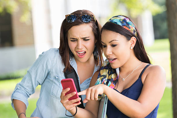 istock College girls making shocked faces while looking at smart phone 514272315