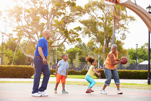 Grandparents And Grandchildren Playing Basketball Together Smiling