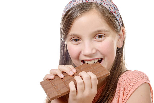 istock pre-teen  girl eats chocolate, isolated on white 514277646