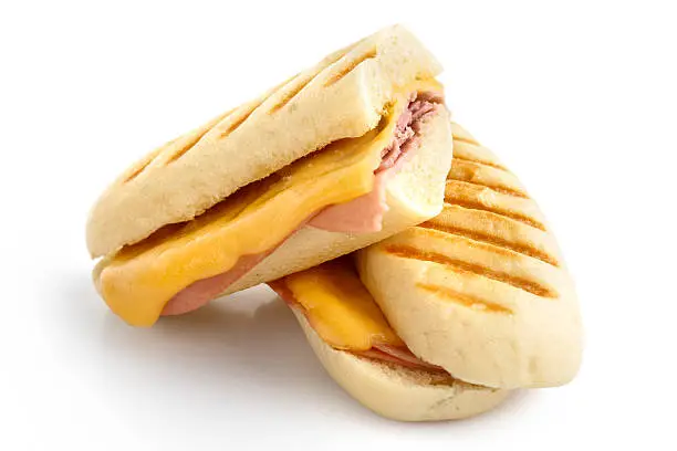 Cut cheese and ham toasted panini melt with grill marks. Isolated on white.