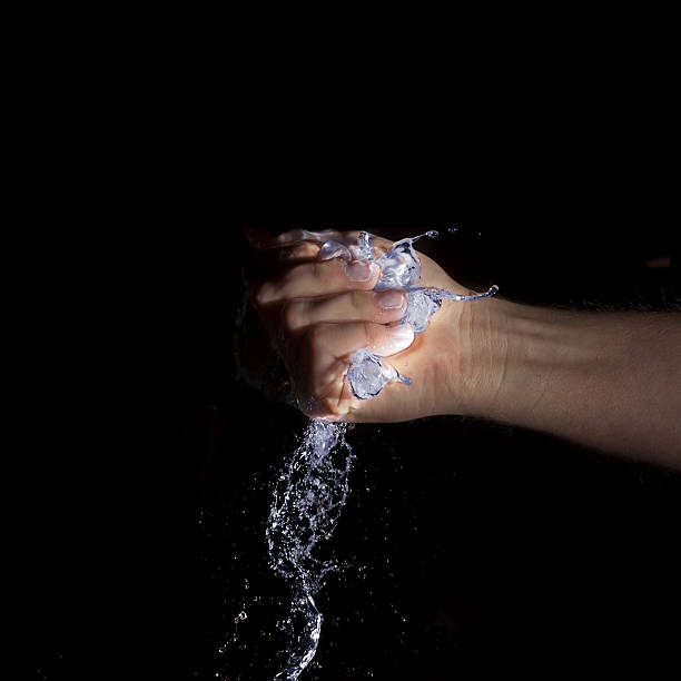 istock hand holding blue glowing water on black background 514295187