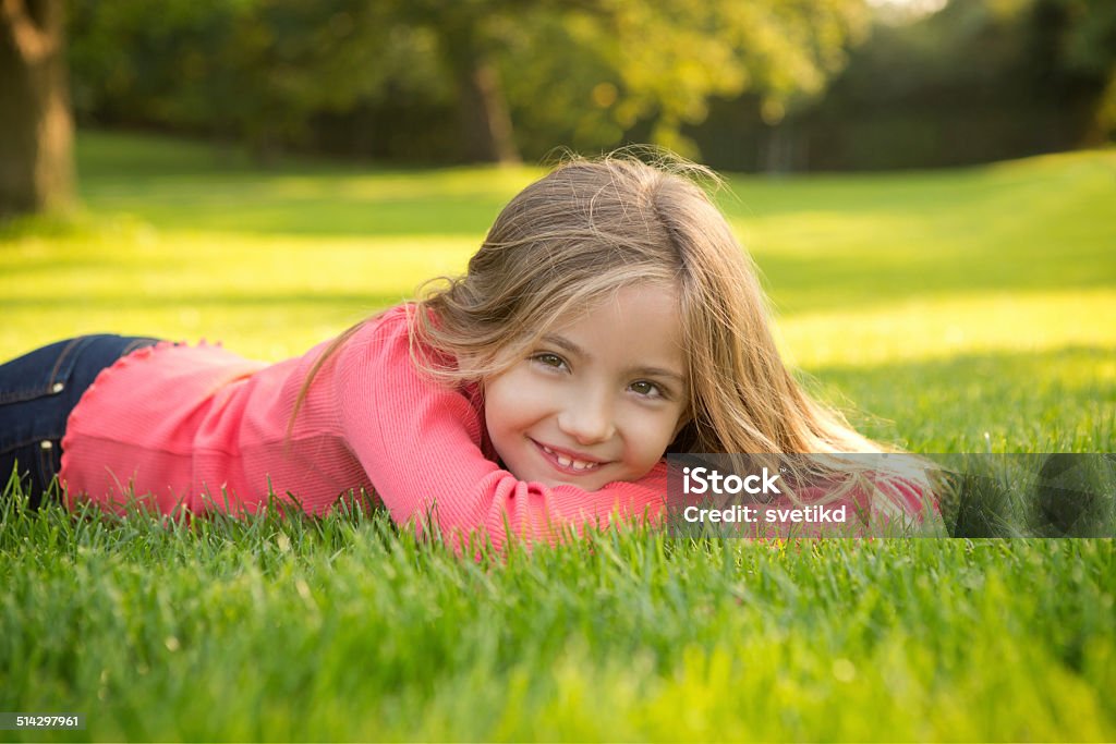 Cute girl in a park. Cute girl lying on grass in park and looking at camera. 8-9 Years Stock Photo