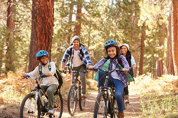 americano africano familia ciclismo a través de bosques otoño - andar en bicicleta fotografías e imágenes de stock