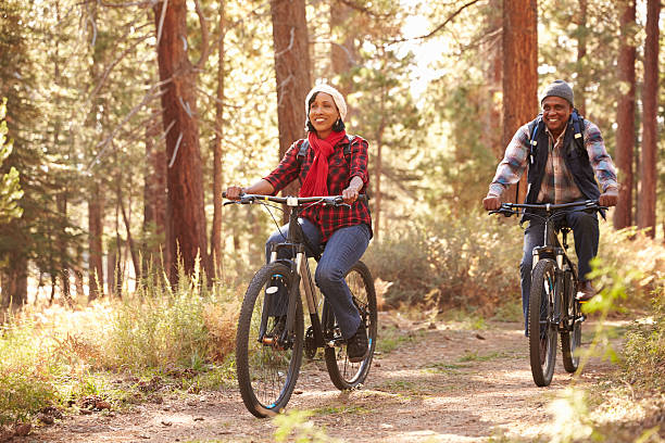 pareja senior ciclismo a través de bosques otoño - african descent cycling men bicycle fotografías e imágenes de stock