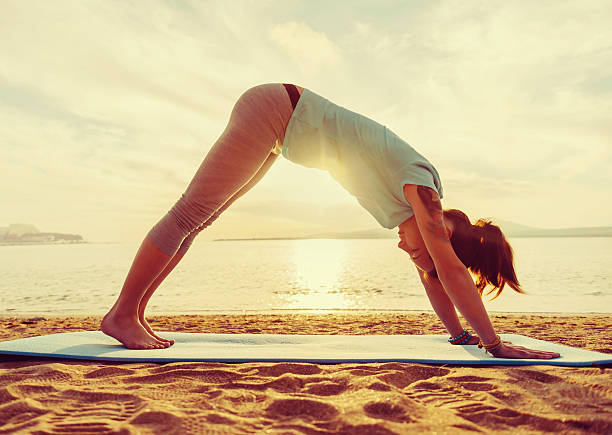 istock Girl practicing yoga on beach 514316860