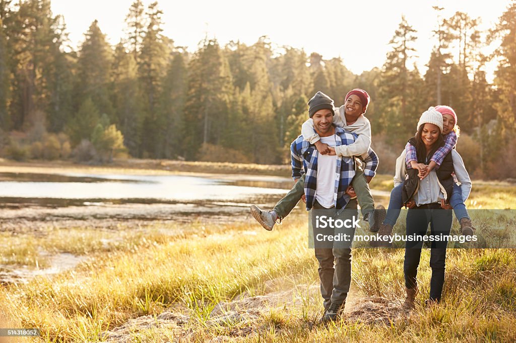 Padres dando Niños De lengüeta Paseo a pie al lago - Foto de stock de Familia libre de derechos