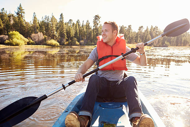 istock Man Wearing Life Preserver Rowing Kayak On Lake 514318194