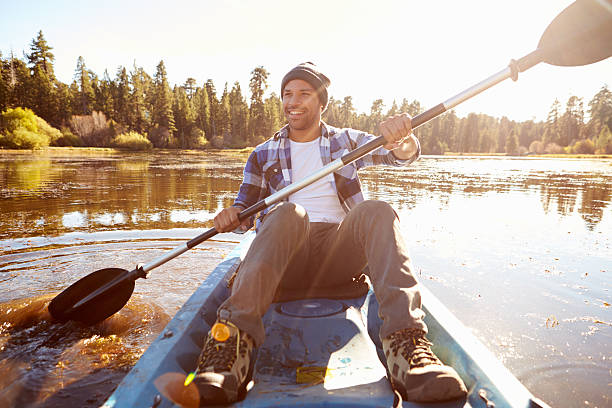 giovane uomo in kayak sul lago di canottaggio - kayaking kayak river sport foto e immagini stock