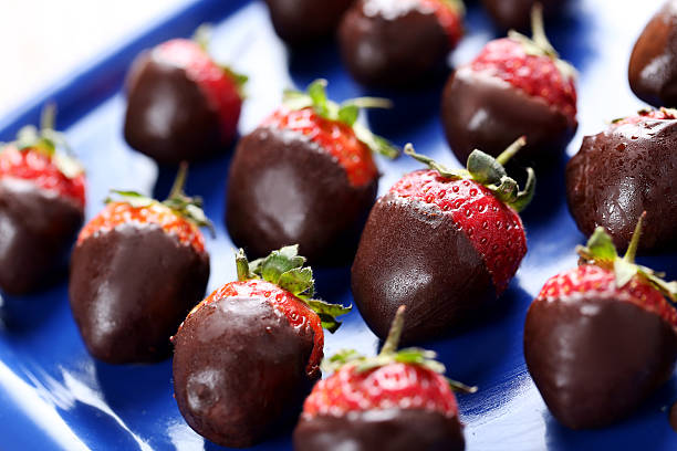 istock Fresh strawberries dipped in dark chocolate on blue tray 514318264