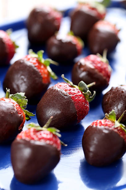 istock Fresh strawberries dipped in dark chocolate on blue tray 514318306