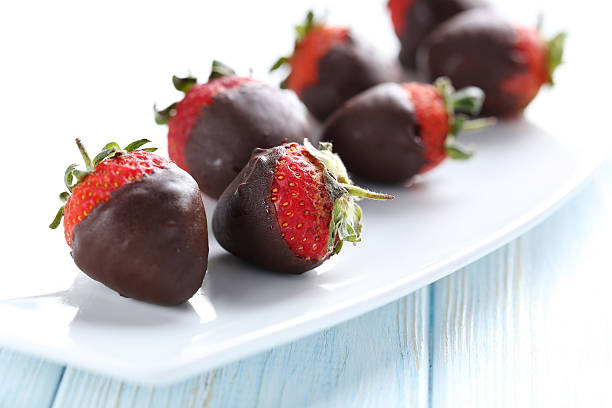 istock Fresh strawberries dipped in dark chocolate on blue wooden backg 514318354