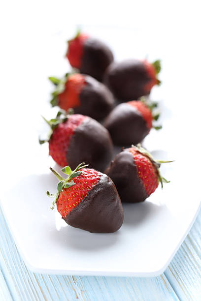 istock Fresh strawberries dipped in dark chocolate on blue wooden backg 514318382