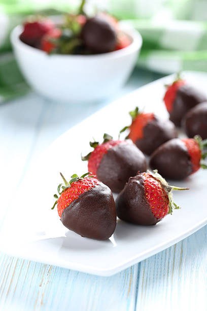 istock Fresh strawberries dipped in dark chocolate on blue wooden backg 514318418