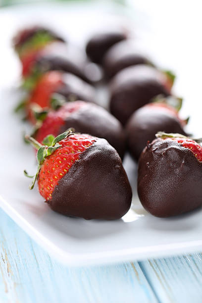 istock Fresh strawberries dipped in dark chocolate on blue wooden backg 514318514