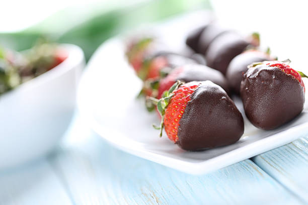 istock Fresh strawberries dipped in dark chocolate on blue wooden backg 514318590