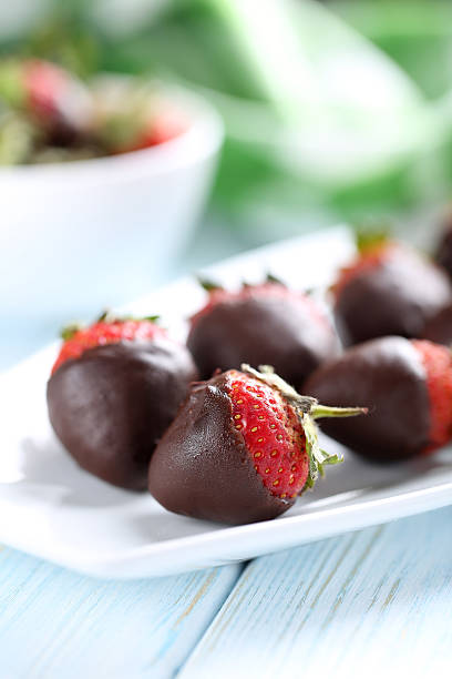 istock Fresh strawberries dipped in dark chocolate on blue wooden backg 514318628