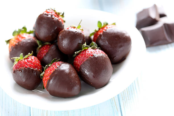 istock Fresh strawberries dipped in dark chocolate on blue wooden backg 514318810