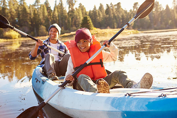 vater und sohn rauen kayak am see - kanus stock-fotos und bilder