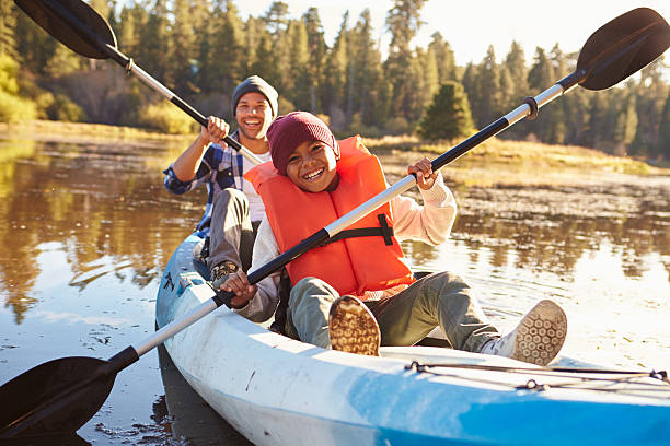 Father And Son Rowing Kayak On Lake Father And Son Rowing Kayak On Lake using a paddle stock pictures, royalty-free photos & images