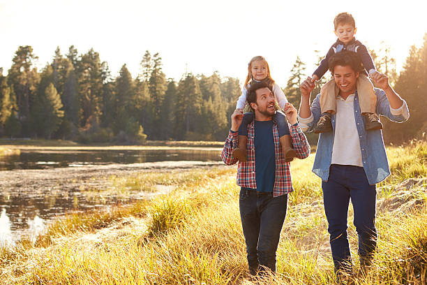 gay männchen paar mit kindern zu fuß von lake - family four people smiling autumn stock-fotos und bilder