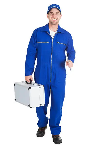 Full length portrait of happy worker with toolkit and wrench over white background