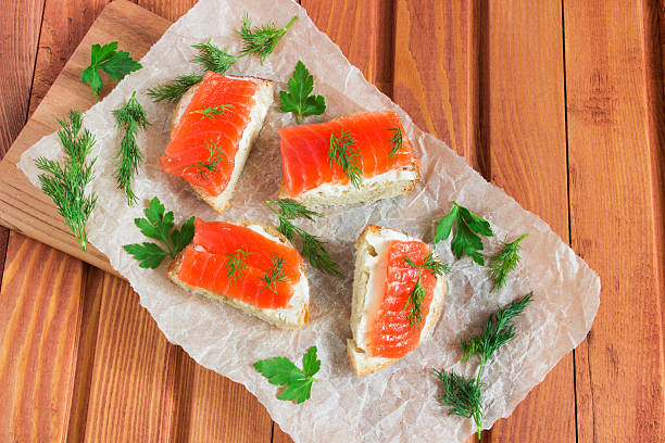 Sandwich with salted salmon and butter and spices Sandwich with salted salmon, butter, dill, parsley, and spices on wooden table sandwich new hampshire stock pictures, royalty-free photos & images