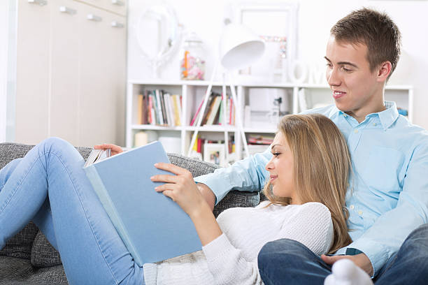 istock Young couple sitting on the sofa and reading a book 514320764