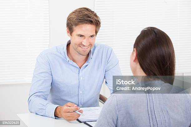 Businessman Checking Resume Of Female Candidate During Meeting Stock Photo - Download Image Now