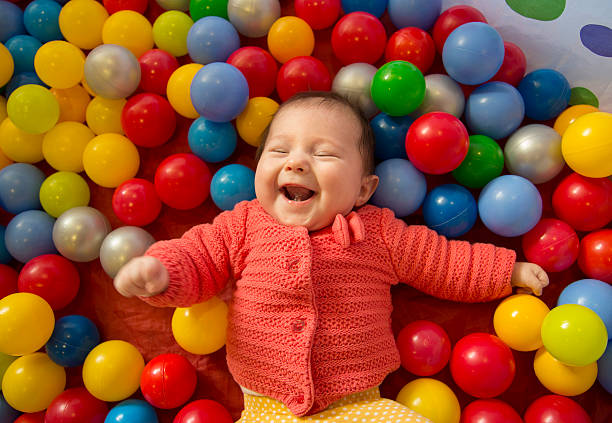 baby girl in a ball pit baby girl laughing in a sensory ball pit sensory perception stock pictures, royalty-free photos & images