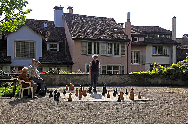 Zurich, Switzerland - May 05, 2013: Old buildings and local men play traditional oversized street chess in the Lindenhof Park , center of Zurich, Switzerland.