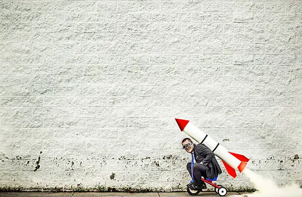 Businessman riding a tricycle and getting help from the rocket strapped to his back :-)