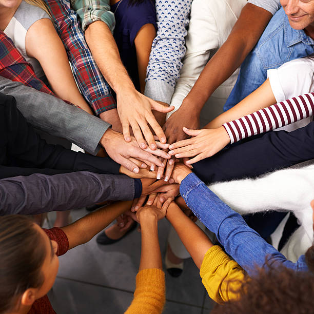 Every effort to keep the unity in spirit Shot of a diverse group of business people joining their hands in a symbol of unity hands clasped stock pictures, royalty-free photos & images