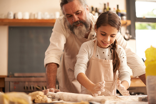 Shot of a girl bonding with her grandfather as they bake in the kitchen
