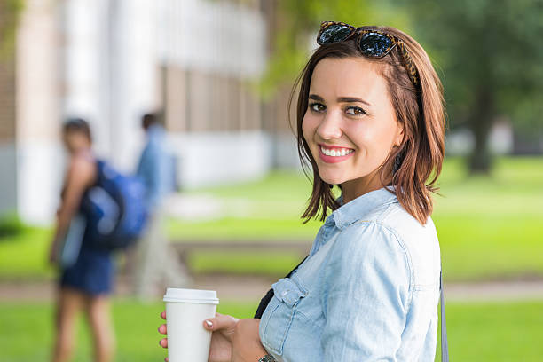istock Cute girl smiling while having coffee on beautiful college campus 514344549