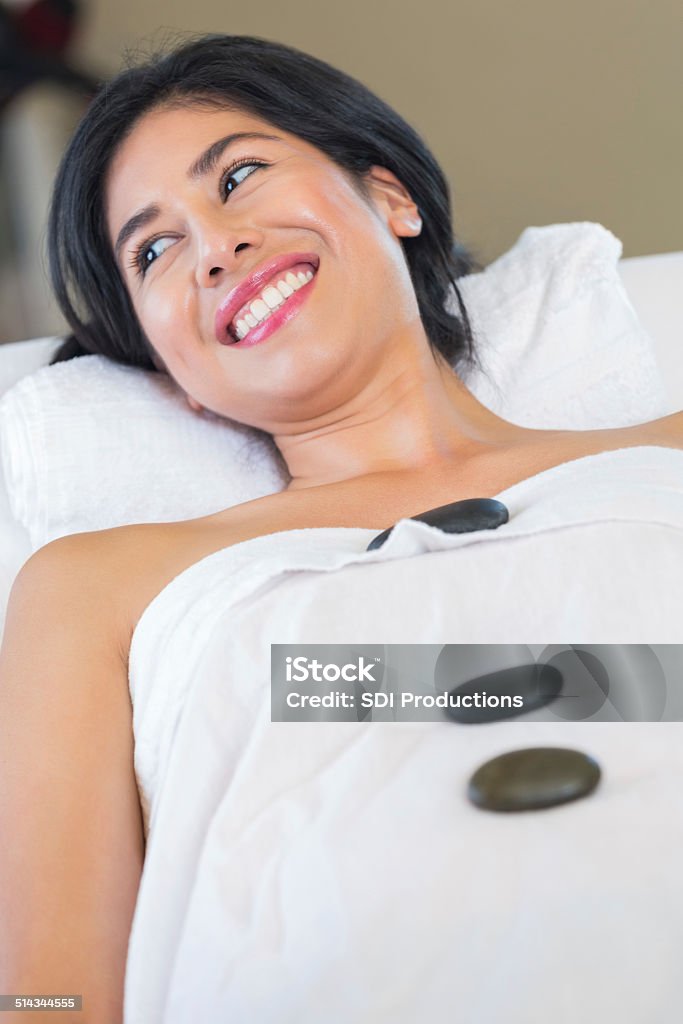 Happy spa customer smiling during cold stone therapy relaxation treatment Woman relaxing with cold stone therapy during spa massage Adult Stock Photo