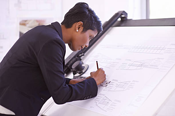 Showing extreme skill at the drawing board Cropped shot of a female architect working on a building plan at a drawing board drawing board stock pictures, royalty-free photos & images